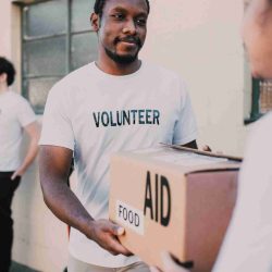 Man in White Crew Neck T-shirt Holding Brown Box